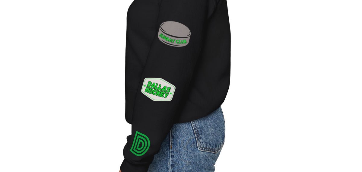 Woman wearing black Dallas-themed crewneck sweatshirt with green and white custom patches on the left sleeve, including dallas hockey patch and hockey puck. Streetwear fit from Sunday Club.